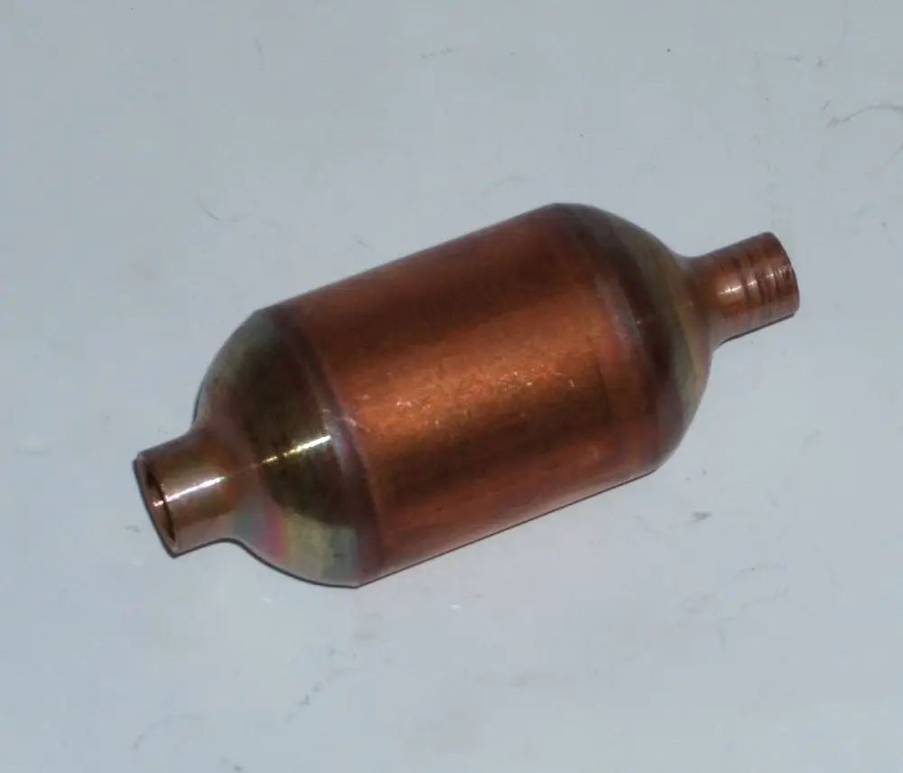 Kupferner Schalldämpfer von Daikin mit zwei anschraubbaren Ausgängen an den Enden. Rotierende Form mit mittlerem Durchmesser, abgebildet auf hellem Untergrund.